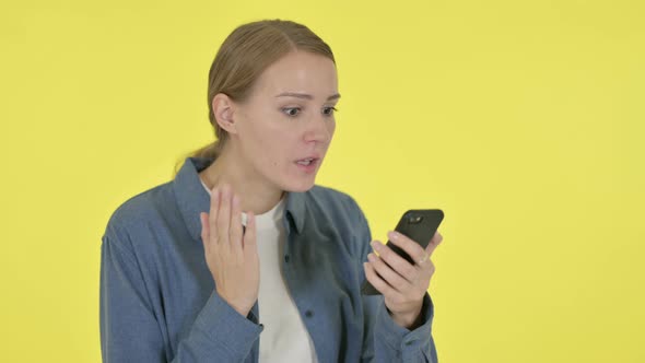 Young Woman Loss on Smartphone on Yellow Background