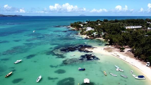 Slow aerial birds eye shot of sandy beach,villas and boats on turquoise sea