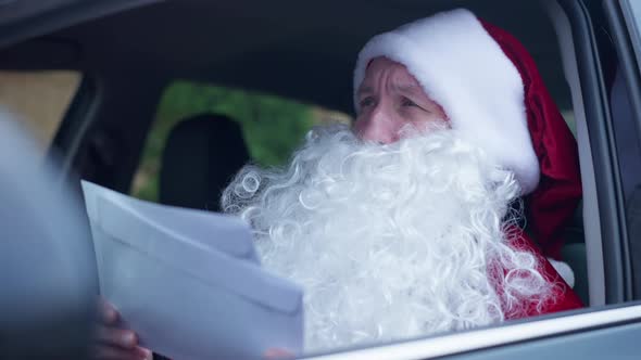 Busy Santa Clause Sitting in Car Reading Letters Envelopes Looking Around