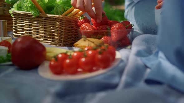 Unrecognized Hands Take Strowberry on Picnic Closeup