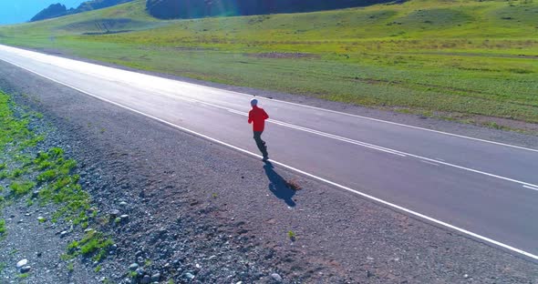 Low Altitude Flight in Front of Sporty Man at Perfect Asphalt Road