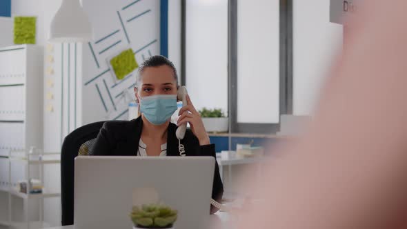 Entrepreneur with Protective Face Mask Discussing on Landline