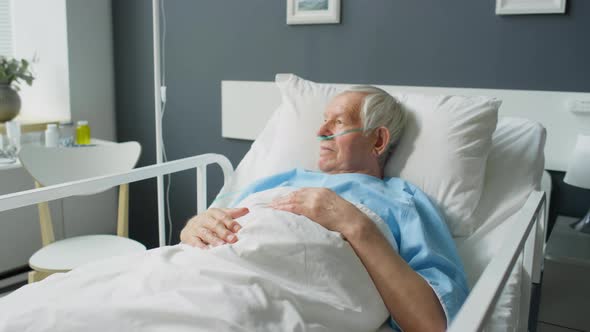 Elderly Patient with Nasal Cannula Lying in Hospital Ward
