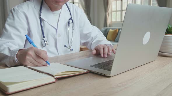 Man Doctor Working On Laptop Computer And Write On Note Book