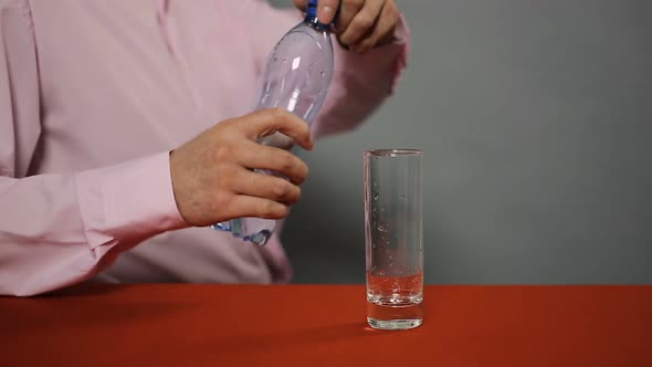 Man Sitting in Cafe and Pouring Bottled Sparkling Mineral Water Into Glass