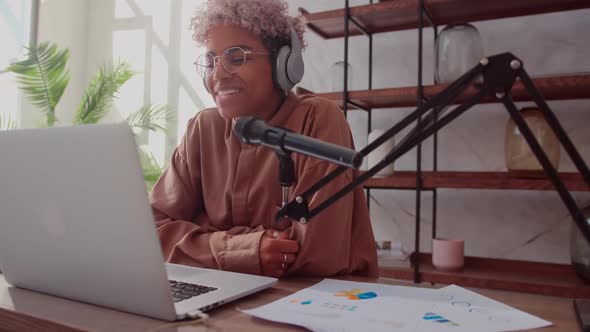 Woman with Microphone and Headphones Talking and Recording Podcast at Studio