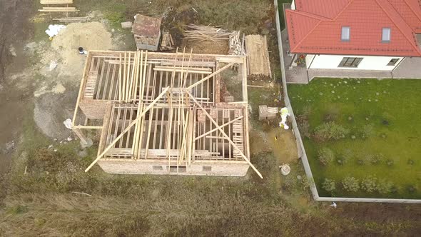 Top Down Aerial View of Two Private Houses One Under Construction with Wooden Roofing Frame and