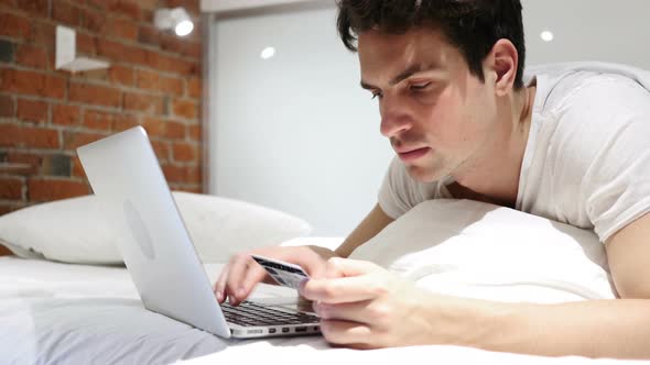 Online Shopping by Man in Bed, Payment by Credit Card