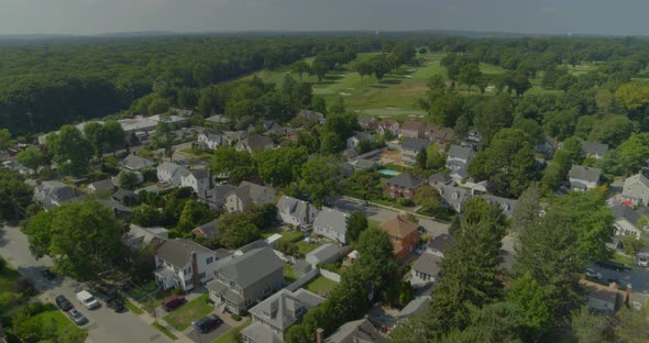 Flying Over Suburban Homes and Towards Golf Course Near Forest in Long Island