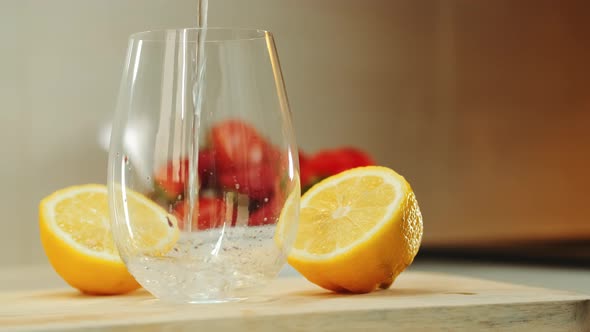 Empty Glass Between Two Part of Cut Lemon on Wooden Cutting Board