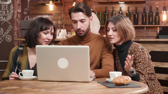 Young Designer Presenting a Project To His Female Colleagues During a Coffee Break