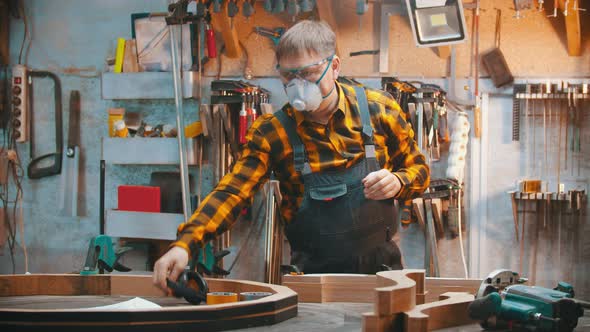 Carpentry Indoors - a Man Woodworker Put on a Protective Mask and Soundproof Headphones