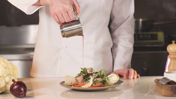 Young Talented Chef Decorates Salad and Pours It with Sauce