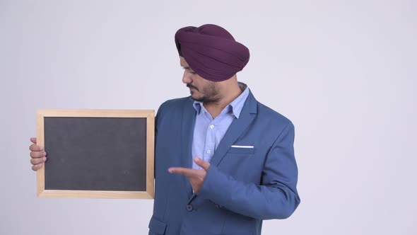 Happy Bearded Indian Sikh Businessman Holding Blackboard and Giving Thumbs Up