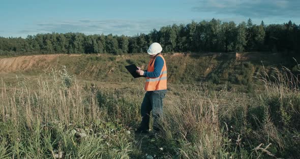 Working Engineer in White Helmet Next to a Sand Pit