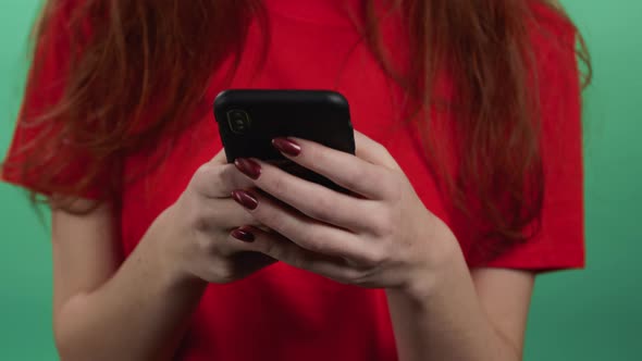 Hands of Woman Using Mobile Phone on Green Background