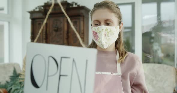 Young Woman Florist Closing Her Flower Store Due to Pandemic Lockdown Viewed Through Glass Door