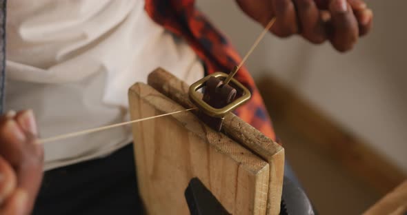 Hands of african american craftsman preparing belt in leather workshop