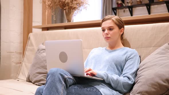 Shocked Wondering Woman Working on Laptop Sitting on Sofa at Home