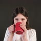 A pretty smiling girl is drinking coffee, isolated on a gray screen background. - VideoHive Item for Sale