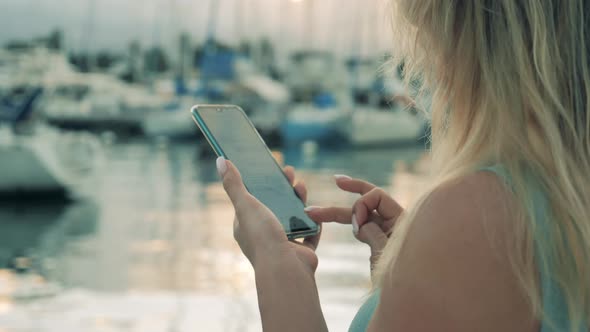 Woman Stands in Docks Near Water, Working with Phone.