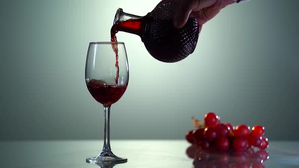 Man's Hand Pours Red Wine Into a Glass From a Decanter