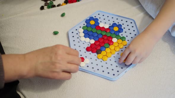 Children's Hands and the Hands of an Adult Play a Children's Game Collect a Colored Mosaic on a