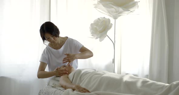 Asian Woman Cosmetologist Is Massaging Face of Female Client of Spa Salon