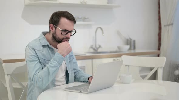 Serious Young Beard Young Man Thinking and Working on Laptop