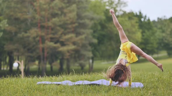 A Little Girl Performs the Elements of Rhythmic Gymnastics in the Park