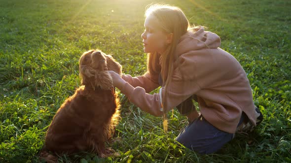 Fair Haired Girl in Hoodie and Jeans Kisses Furry Spaniel