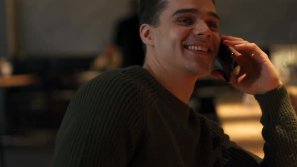 Cheerful man wearing sweater talking by phone