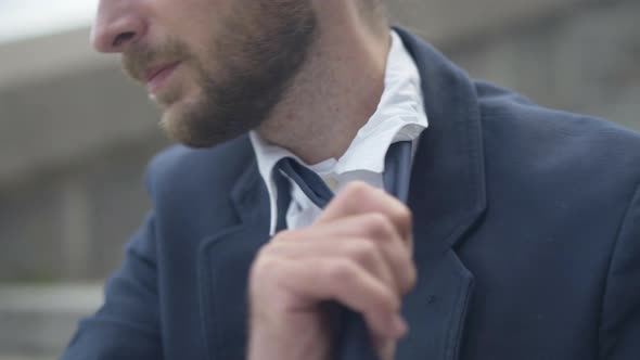 Unrecognizable Exhausted Businessman Loosing Necktie and Sighing. Tired Young Caucasian Bearded Man