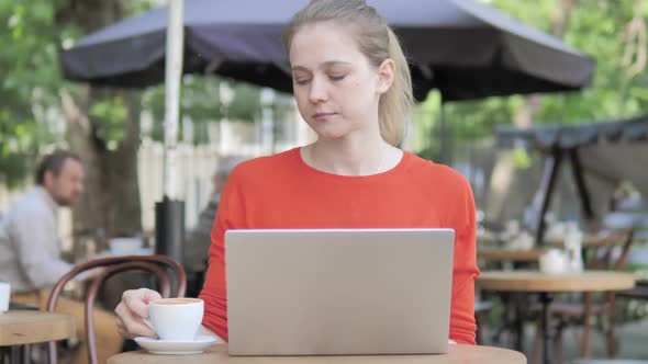 Young Woman Working on Laptop and Drinking Coffee Sitting in Cafe Terrace