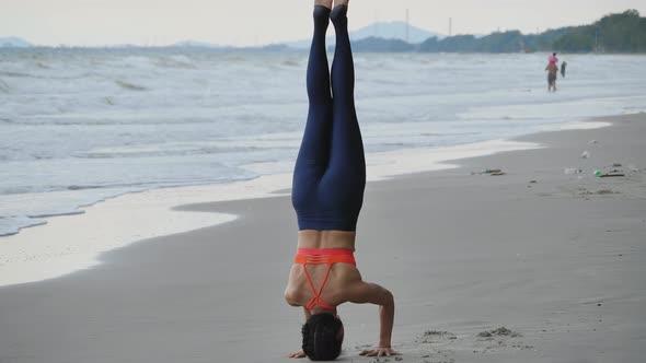 Asian woman is practicing yoga position on the beach.