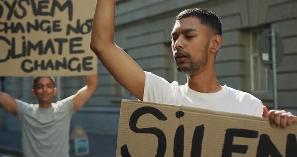 Two mixed race men on a protest march holding placards raising hands and shouting