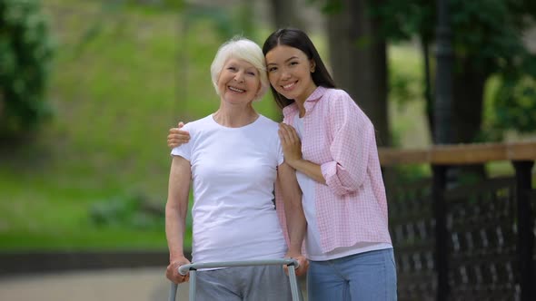 Volunteer and Disabled Old Woman Smiling Into Camera in Hospital Park, Care