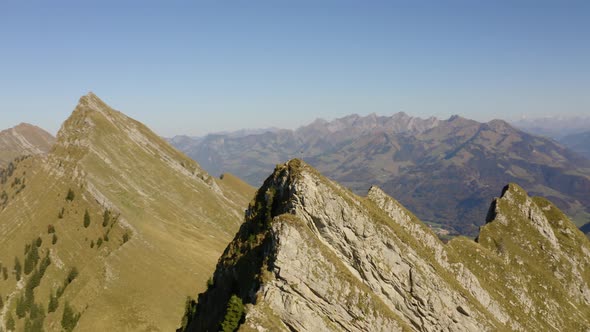 Fast aerial orbit around summit with cross on top. The Alps in the background and autumn colors