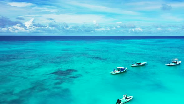 Small boats floating over quiet turquoise lagoon with clear water and coral reef patterns bordered b