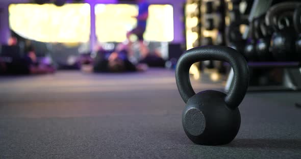 A kettlebell weight in a gym with people working out in a fitness training class in the background S