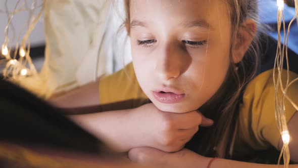 Family Bedtime Pretty Girl Reading Book in a Tent House at Night