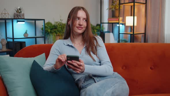 Young Pretty Woman Sitting on Sofa Using Smartphone Share Messages on Social Media Application Chat