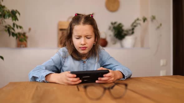 Poor eyesight Little girl in play game on smarthone