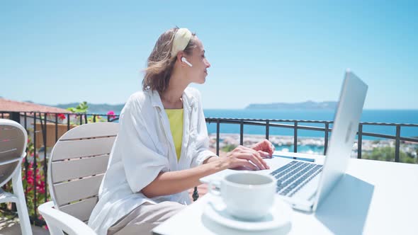 Young Mixed Race Female Specialist in Wireless Headset Holding Video Call on Laptop Remote Work