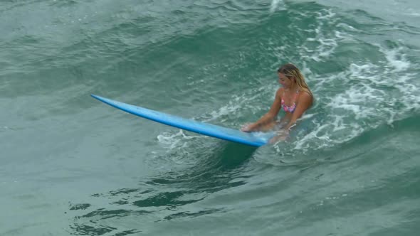 A young woman surfing in a bikini on a longboard surfboard.