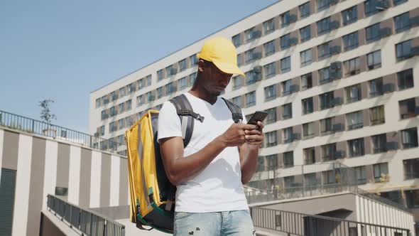 African Courier Looks at His Smartphone Checking His Destination