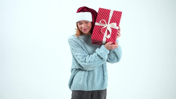Happy Young Girl in Santa Claus Cap Holding Present