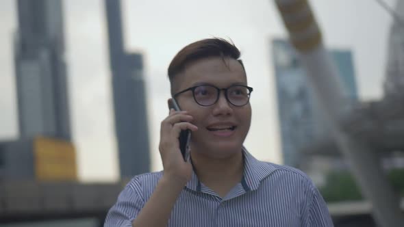 Portrait handsome Asian businessman talking phone with a friend walking on the urban city.