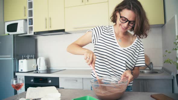 Young Cheerful Woman Mixing the Chocolate Dough in a Bowl