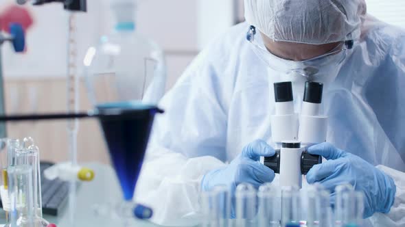 In Modern Laboratory Scientist in Coverall Is Looking in Microscope alt
